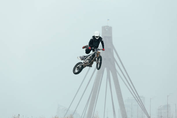 Portrait of bearded man motocyclist in dark sunglasses on dark building background