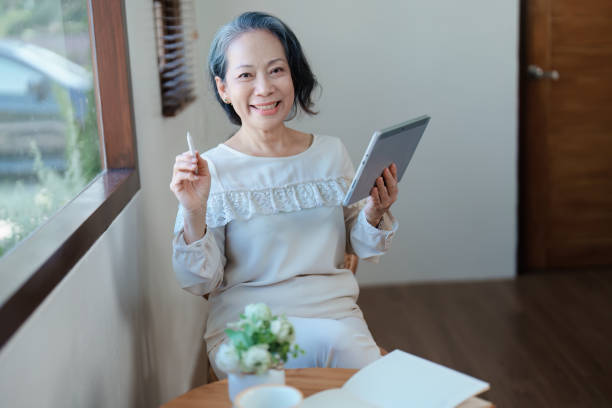 istock Portrait of an elderly Asian woman in a modern pose working on a tablet computer. 1466291762