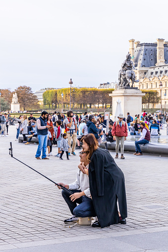 Couple of japanese tourists taking a selfie with their phone on a stick in Paris, France
