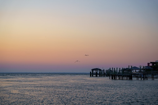 The pastel sunset sky over the ocean and wooden structures  by Saint George Island, Florida