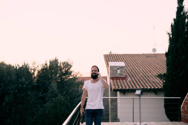A young handsome man excited having a fun phone call while walking in his house