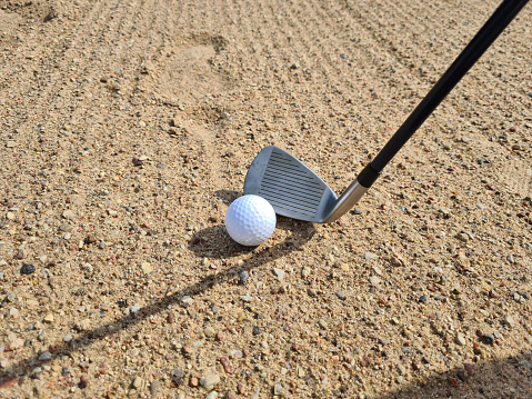 Golf shot from sand bunker golfer hitting ball from danger. Sand golf course
