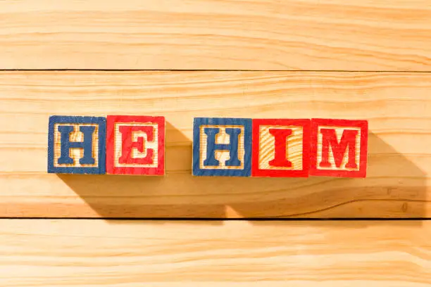 Spectacular wooden cubes with the word HE HIM on a wooden surface