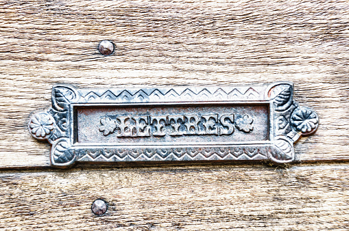 A closeup shot of an old metal antique plaque on a mailbox with letres text engraved on it