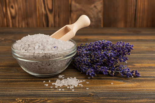 Lavender flowers and fragrant sea salt. The concept of spa, beauty and health salon, skin care cosmetics. Natural cosmetics.Aroma procedures. Close up photo on white wooden background.