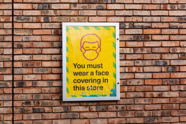 istock Large sign is mounted on a brick wall stating that a face covering must be worn while in the store 1466312192