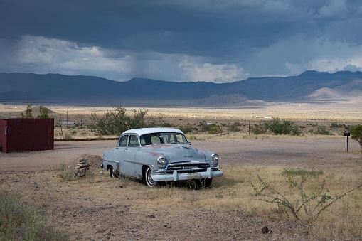 Arizona, United States – November 09, 2022: An old blue-gray 1954 Chrysler Windsor with a white top abandoned on a desert road