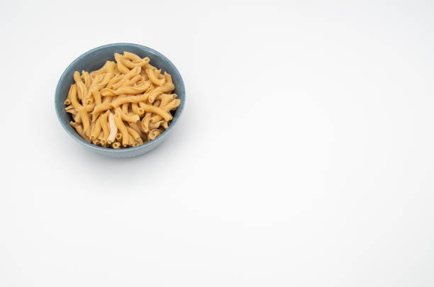 Top view of a bowl of cooked pasta on a white background with copy space on the right