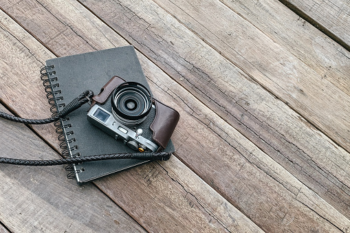 An old, vintage camera with a notepad on a wooden surface