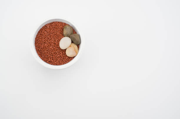white vase filled with terracotta color decorative sand on white background with space for text