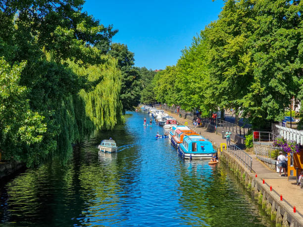 istock Pleasure boaters and paddle boarders on a river running through Norwich 1466320961