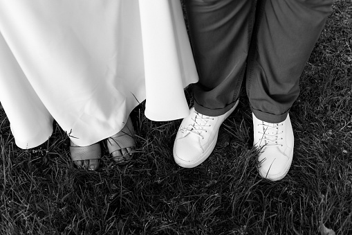 A grayscale shot of the feet of bride and groom on the grass