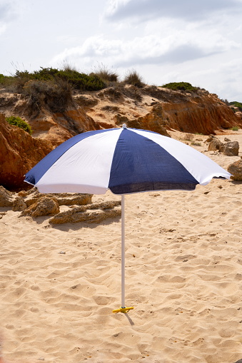 A blue and white parasol in the sand on the beach