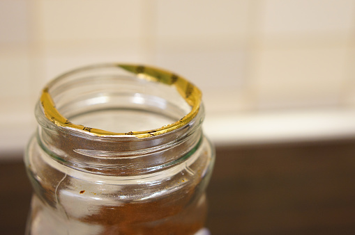 A shallow focus shot of an open transparent jar isolated on a brown background