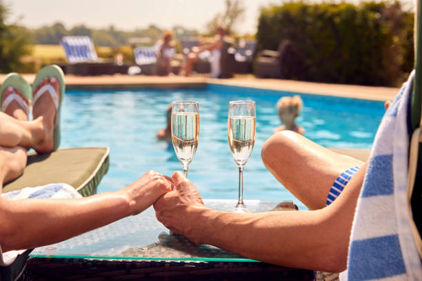 Zbliżenie pary na leżakach trzymających się za ręce przy basenie na wakacjach pijących szampana – zdjęcie