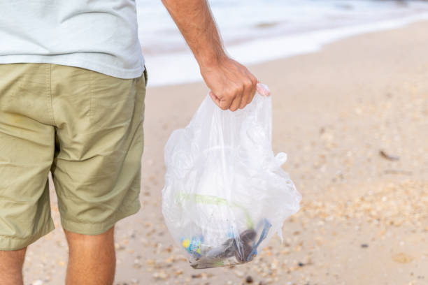 istock Man picks up plastic trash on the each in the morning 1466325403