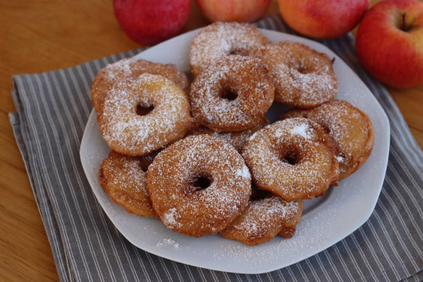 istock Fried apple rings with batter sprinkled with powdered sugar on a plate on wooden table with fresh apples 1466325840