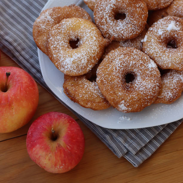 istock Fried apple rings with batter sprinkled with powdered sugar on a plate on wooden table with fresh apples 1466325858