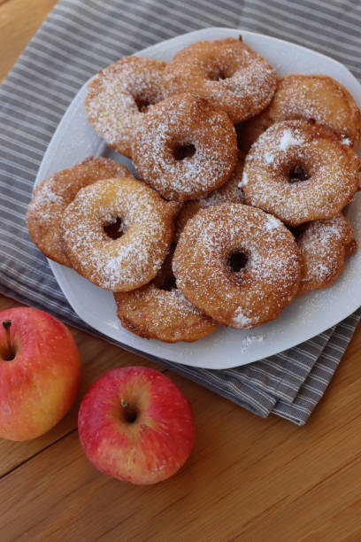 istock Fried apple rings with batter sprinkled with powdered sugar on a plate on wooden table with fresh apples 1466325918