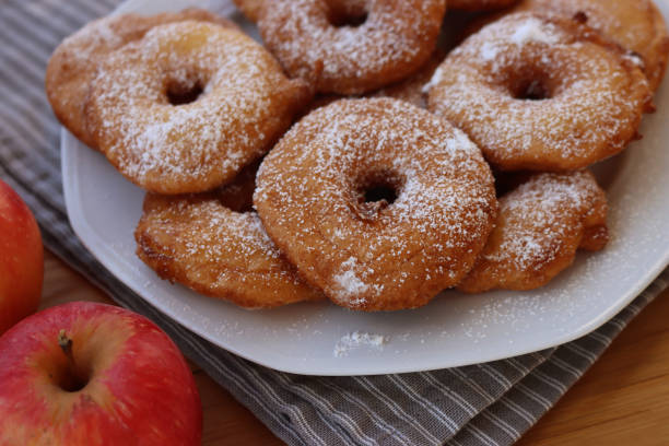 istock Fried apple rings with batter sprinkled with powdered sugar on a plate on wooden table with fresh apples 1466325962