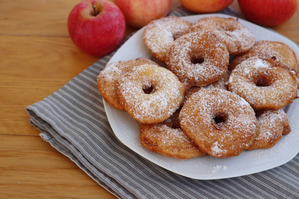 istock Fried apple rings with batter sprinkled with powdered sugar on a plate on wooden table with fresh apples 1466325969
