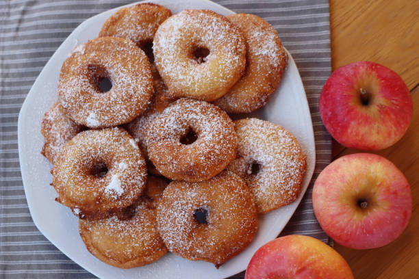 istock Fried apple rings with batter sprinkled with powdered sugar on a plate on wooden table with fresh apples 1466326044