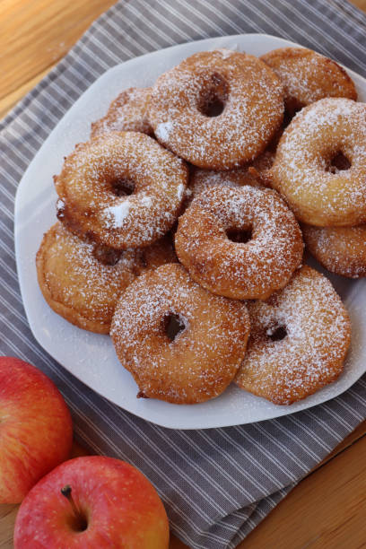 istock Fried apple rings with batter sprinkled with powdered sugar on a plate on wooden table with fresh apples 1466326047