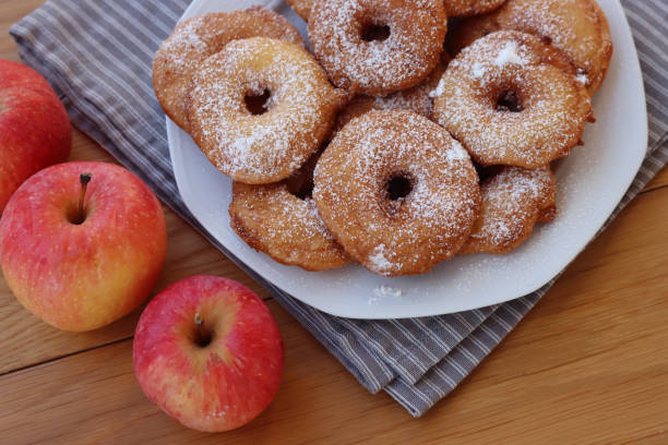 istock Fried apple rings with batter sprinkled with powdered sugar on a plate on wooden table with fresh apples 1466326112
