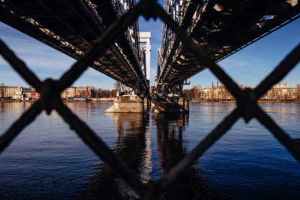 closeup of a bridge over the river through a rusty cyclone fence - cyclone fence imagens e fotografias de stock