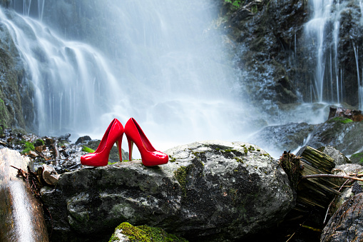 A pair of red high heels on a rock at the waterfall in the Black Forest
