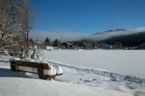 A beautiful shot of a wooden bench fully covered in snow on a winter morning