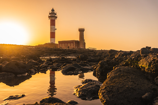 The Toston Lighthouse with its reflection in the water at sunset in Punta Ballena, Fuerteventura island, Canary Islands, Spain