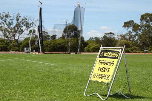 A yellow warning sign for field events at an sporting or atheletics carnival or competition. Exercise caution around throwing events such as javelin, shot-put, discus and hammer throw.