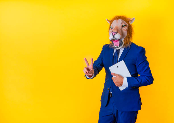 istock Unrecognizable businessman with lion mask making victory gesture and holding tablet 1466335943