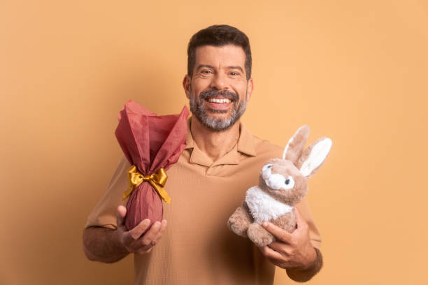 istock joyful senior man showing easter egg in beige colors. holiday, easter, celebration concept. 1466336284