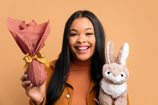 happy black young woman with easter bunny in all beige colors. holiday, easter, celebration concept.