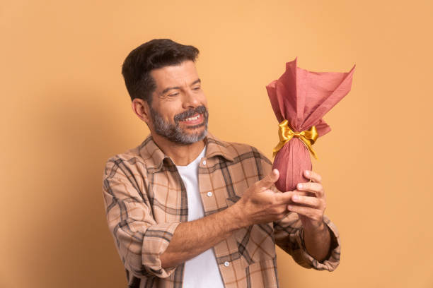 istock happy senior man celebrating easter egg gift in all beige colors. holiday, easter, celebration concept. 1466336418
