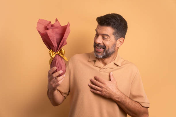 istock happy senior man offering easter egg in all beige colors. holiday, easter, celebration concept. 1466336473