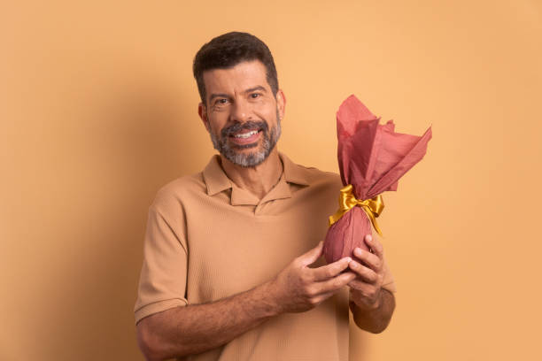 istock happy brazilian man showing easter egg in beige background. holiday, easter, celebration concept. 1466336515