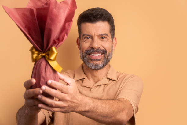 istock joyful mature man celebrating easter egg gift in beige background. holiday, easter, celebration concept. 1466336532