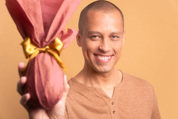 istock joyful brazilian man showing easter egg in studio shot. holiday, easter, celebration concept. 1466336578