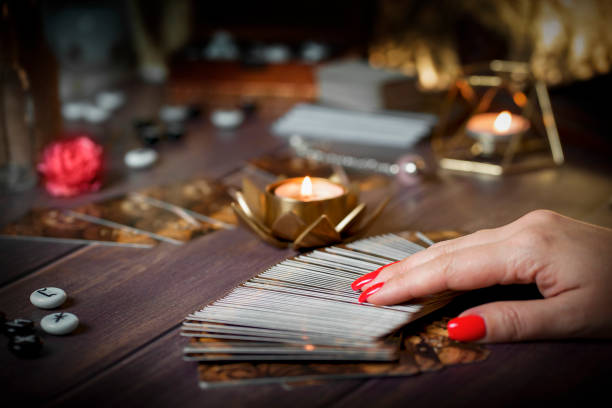 Fortune-telling on traditional tarot cards on the table with a candle Tarot card reader arranges cards in a card spread.Fortune-telling on traditional tarot cards on the table with a candle. Selective focus. tarragon horizontal color image photography stock pictures, royalty-free photos & images