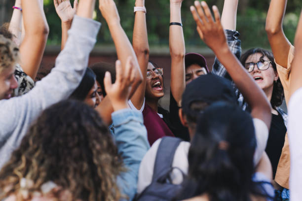 giovani felici che applaudono a un evento scolastico - cheering arms raised women university foto e immagini stock