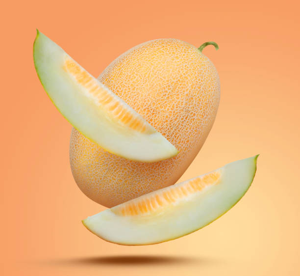 istock Delicious ripe melons falling on pale orange background 1466349141