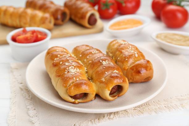 istock Delicious sausage rolls and ingredients on white wooden table 1466351582