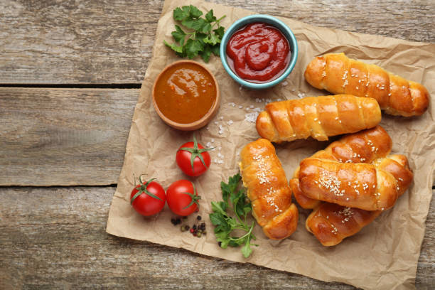 istock Delicious sausage rolls and ingredients on wooden table, top view. Space for text 1466351589