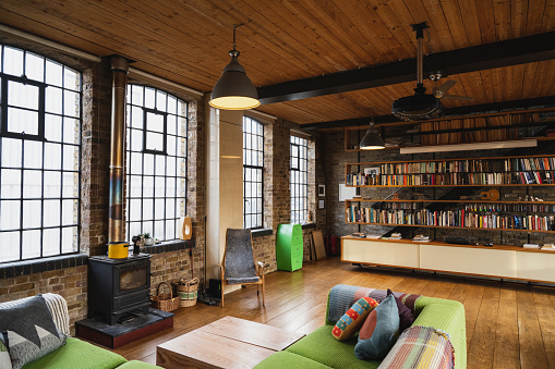Stylish home interior of converted industrial warehouse with wood floor and ceiling, steel industrial style windows.