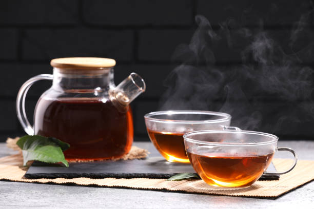 istock Aromatic hot tea in glass cups and teapot on light grey table near brick wall 1466351871