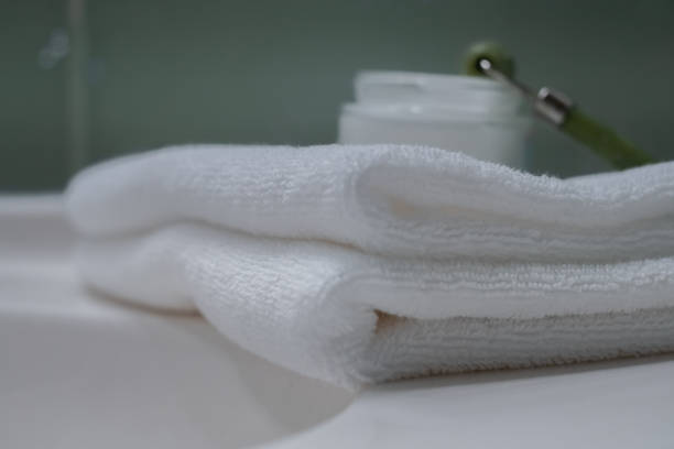istock Stack of fresh towels and face roller on countertop in bathroom 1466354765