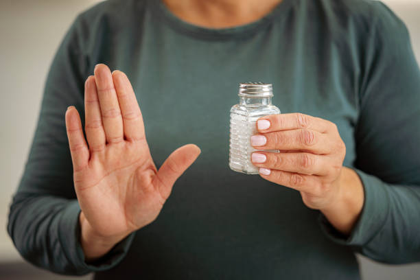 Woman holding salt shaker and showing stop gesture